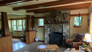 Una sala de estar acogedora con chimenea de piedra, vigas de madera, un sofá de cuero y un comedor con mesa de madera.