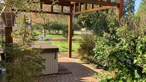 Una estructura de pérgola de madera con un sendero de ladrillo que conduce a un cobertizo pequeño.