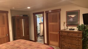 Un dormitorio con una cama grande, un aparador de madera, un cuadro y un televisor.
