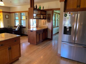 A kitchen with wooden cabinets, a stainless steel refrigerator, and a built-in island with a sink. - New True Country Craftsman (Eugene)