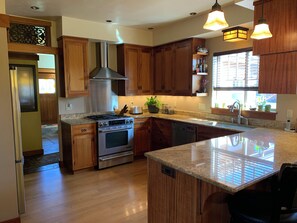A modern kitchen with wooden cabinets, stainless steel appliances, and a large island with a built-in sink. - New True Country Craftsman (Eugene)
