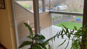 Un balcón con vistas a un patio trasero, una terraza de madera y un área de jardín.