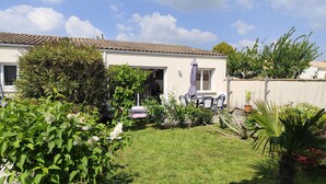 Ein Haus mit Terrasse, umgeben von viel Grün und blauem Himmel.