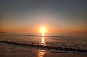 Ein Sonnenuntergang über einem ruhigen Meer mit einer entfernten Küstenlinie.
