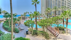 A resort with a pool area, palm trees, and a view of the ocean.