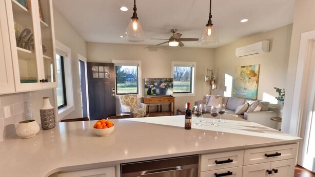 A modern kitchen with a large island, white cabinetry, and a dishwasher.