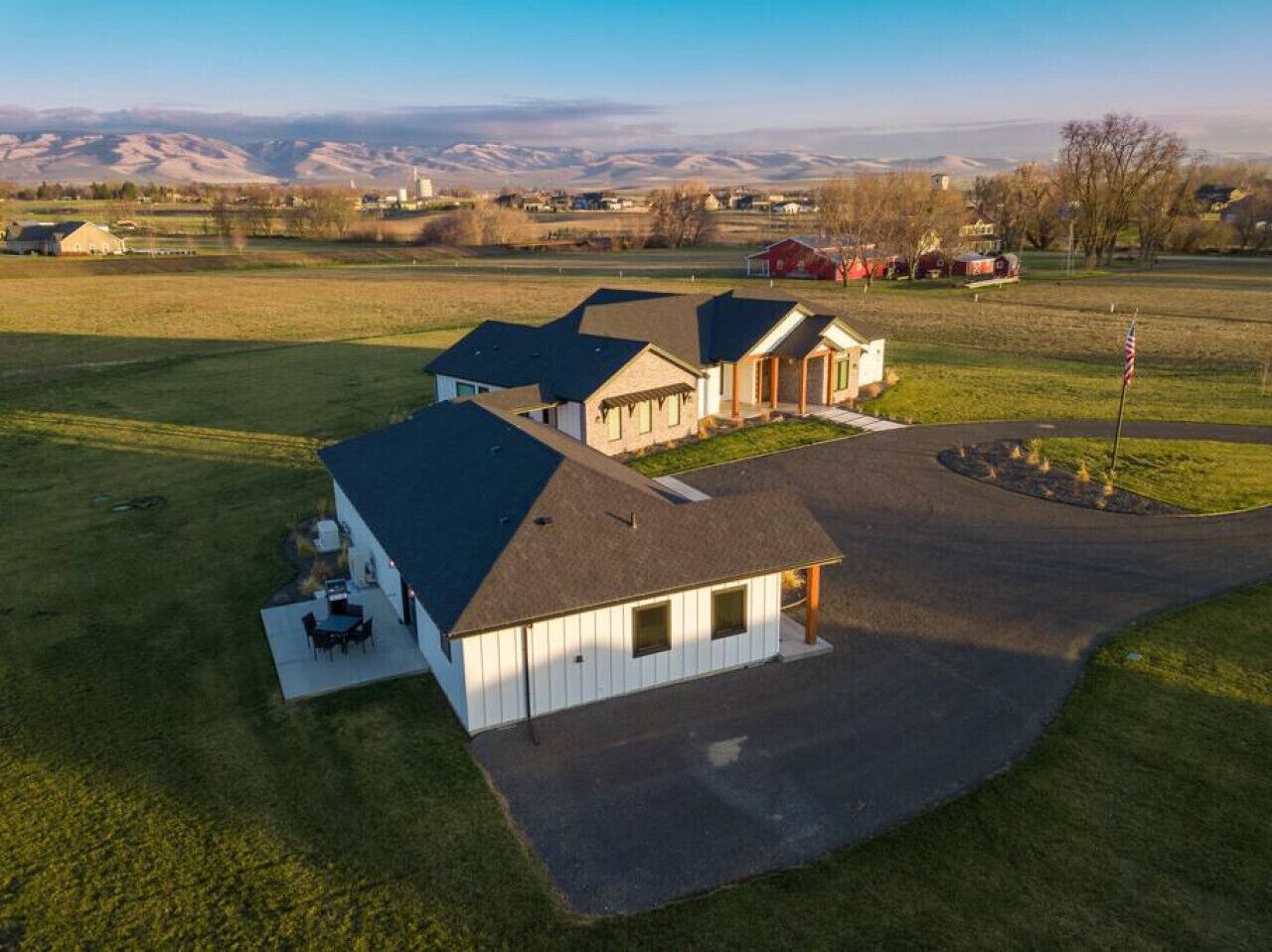 A large, single-story house with a covered patio and a driveway leading to a garage.