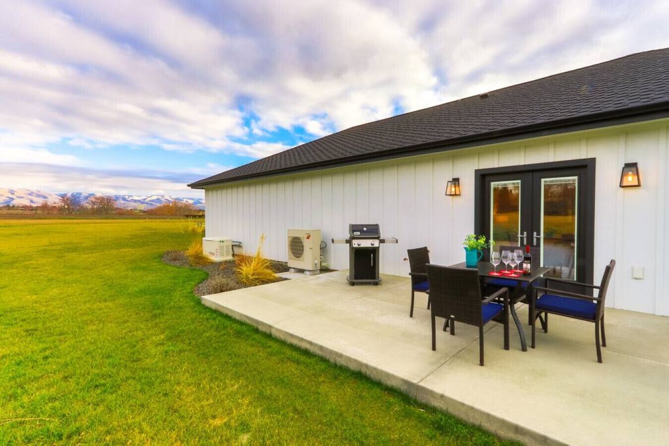 Een huis met een terras, buitenbarbecue en zitgedeelte.