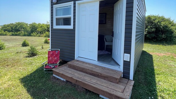A small, single-story cabin with a white door and a small porch. - The Homestead, in Bedeque, waterview beach house and hot tub cabin (Bedeque)