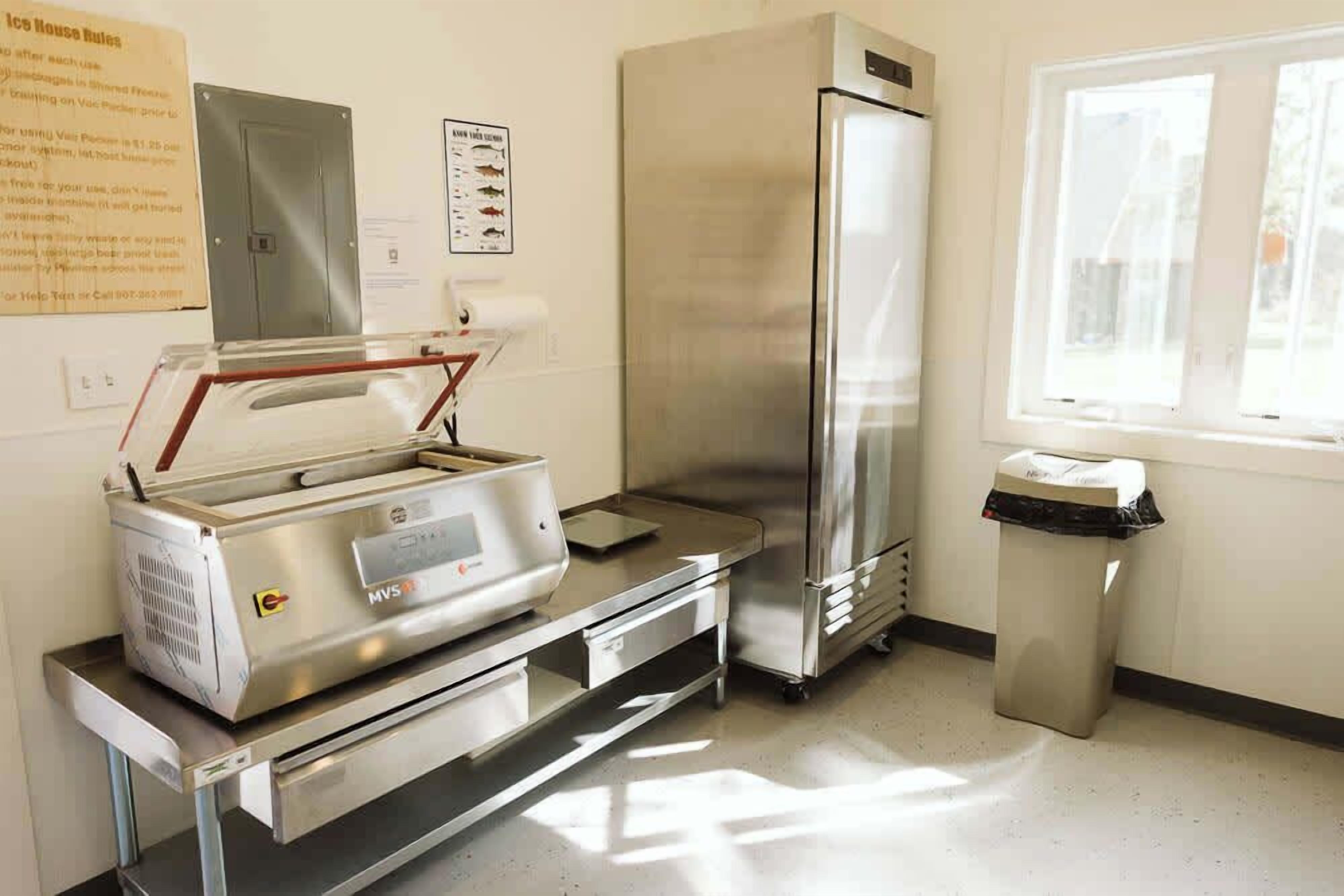 A kitchen with a stainless steel refrigerator, a food warmer, and a trash bin.
