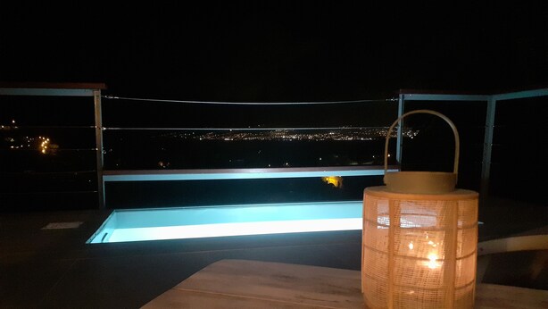 A poolside area with a clear view of the pool and city lights in the background. - Magnificent and luxurious T2 bis (Les Trois Ilets)