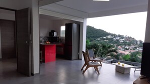 A spacious living area with a view of a hilly landscape. - Magnificent and luxurious T2 bis (Les Trois Ilets)