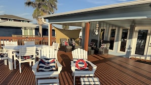 Una terraza con sillas Adirondack blancas, una mesita y una silla reclinable.
