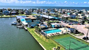 Un puerto deportivo con barcos amarrados, piscina y cancha de tenis.