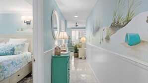 A bedroom with a bed, dresser, and a wall with a painting.