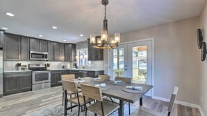 A modern kitchen with dark wood cabinets, stainless steel appliances, and a dining area with a wooden table and chairs. - Massanutten Resort Home w/ Deck + Mountain Views! (McGaheysville)