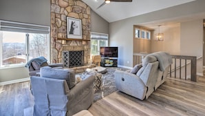 A spacious living room with a stone fireplace, comfortable seating, and a large TV. - Massanutten Resort Home w/ Deck + Mountain Views! (McGaheysville)