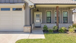 A two-story house with a garage, a front porch, and a brick foundation.