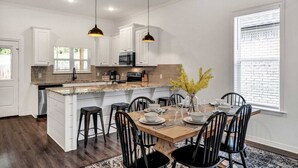 A modern kitchen with white cabinetry, a central island, and pendant lighting.