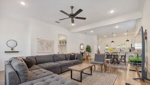 A spacious living room with a sectional sofa, a coffee table, and a dining area with chairs and a table.