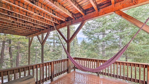 A wooden deck with a hammock, wooden railings, and a view of trees. - Woodland Cabin in Lake Arrowhead: W/Two decks (Lake Arrowhead)