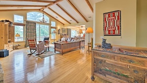 A spacious living room with wooden floors, a large sofa, a rocking chair, and a wooden cabinet with intricate carvings. - Woodland Cabin in Lake Arrowhead: W/Two decks (Lake Arrowhead)