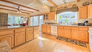 A spacious kitchen with wooden cabinets, a large island, and a view of the outdoors. - Woodland Cabin in Lake Arrowhead: W/Two decks (Lake Arrowhead)