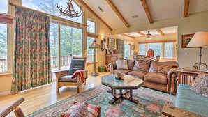 A spacious living room with a large window, a wooden ceiling, and a cozy seating area. - Woodland Cabin in Lake Arrowhead: W/Two decks (Lake Arrowhead)