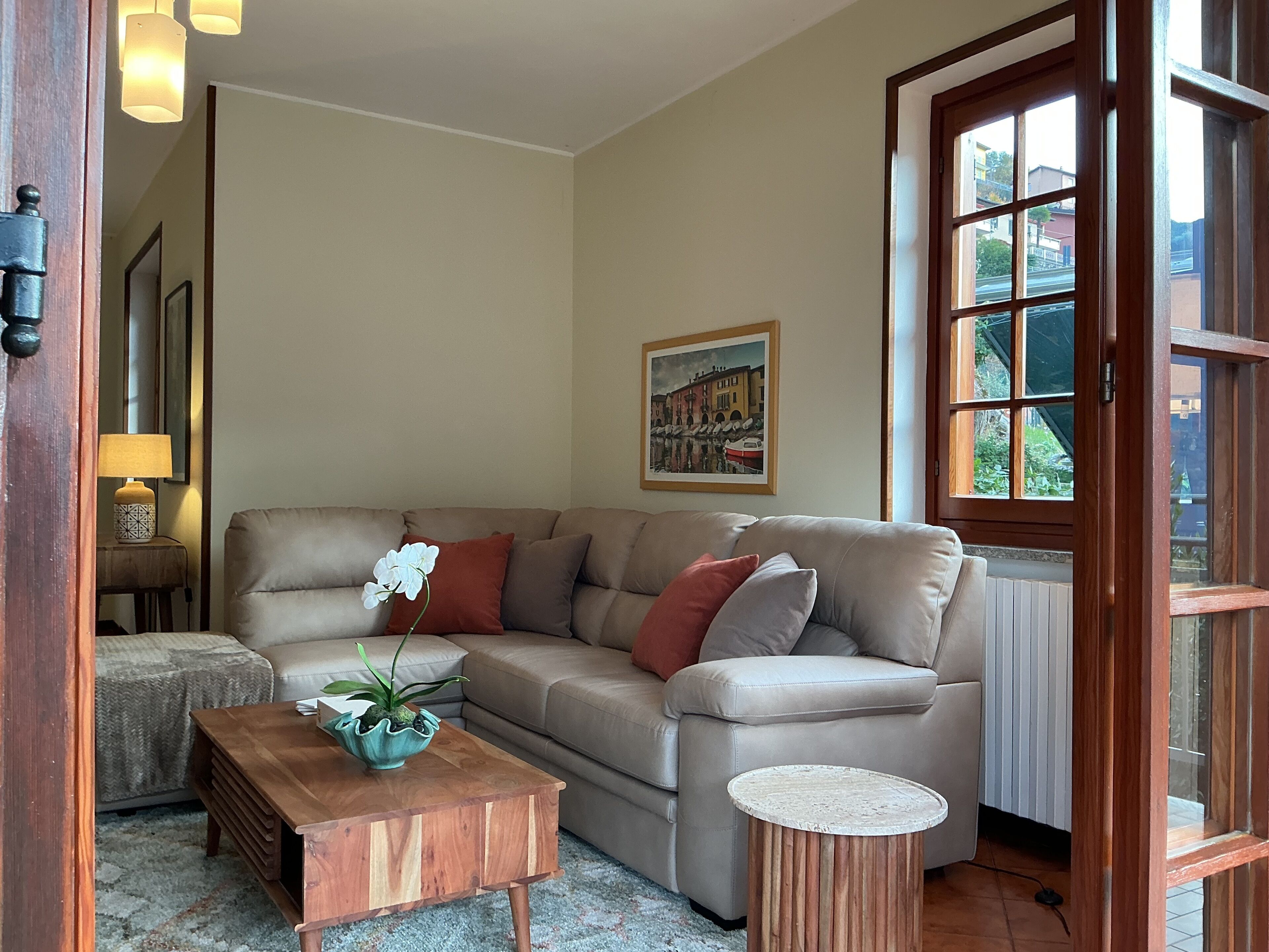 Ein Wohnzimmer mit einem beigefarbenen Sofa, einem Holztisch, einem kleinen Beistelltisch und einer Zimmerpflanze.