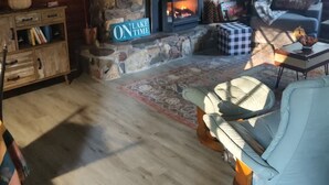 Un salon chaleureux avec une cheminée en pierre, un téléviseur, un canapé et un meuble en bois.