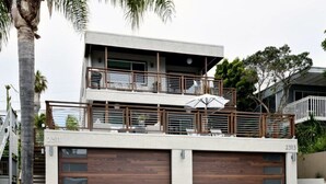 A modern two-story house with a balcony, garage, and a large umbrella. - Luxury Cardiff By-the-sea Ocean View Parkhouse (Cardiff-by-the-Sea)