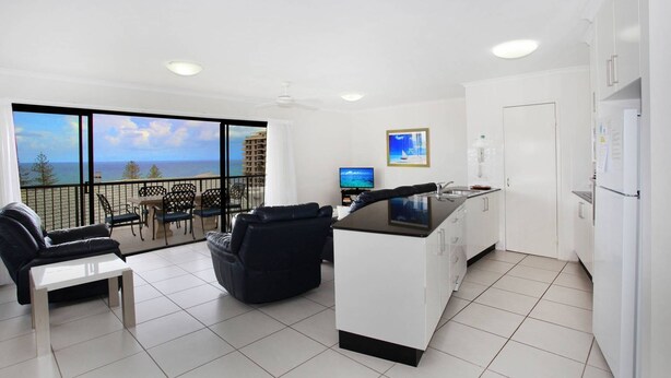 A modern apartment with a balcony, a dining area, a kitchen, and a living room.
