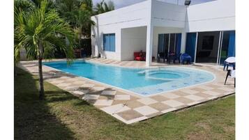 Relax by the rectangular pool surrounded by a checkered tile deck and lush greenery.