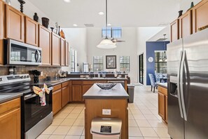 A modern kitchen with wooden cabinets, stainless steel appliances, and a central island. - Luxurious 5BR Villa Your Disney Getaway (Kissimmee)