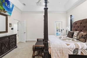 A bedroom with a four-poster bed, a nightstand, a dresser, and a large window with blinds.