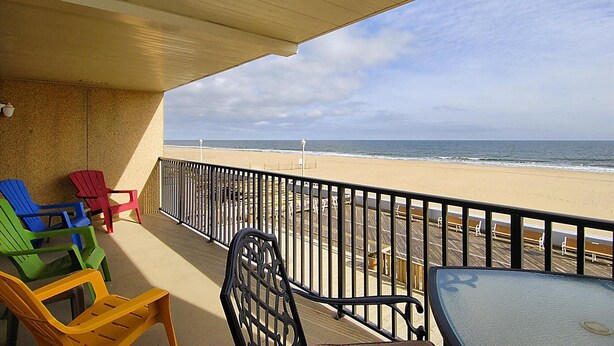 Un balcón con vista a la playa, que incluye una mesa y sillas.