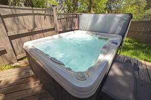 A hot tub with a wooden deck and a wooden fence in the background.
