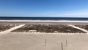 Ein Strand mit blauem Himmel, Sandfläche und einem Weg zum Wasser.