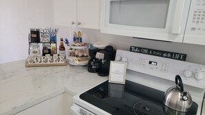 A kitchen with a white microwave, stove, and a sign that says "Take TIME & Enjoy LIFE".
