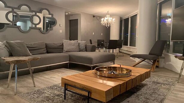 A modern living room with a sectional sofa, a wooden coffee table, and a chandelier. - 3 bedroom Downtown Vancouver S.Penthouse, near skytrain, shopping & restaurants. (Vancouver)
