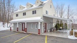 A two-story building with a covered porch and a garage. - Happy Days and Nights - Bear's Den (Harbor Springs)