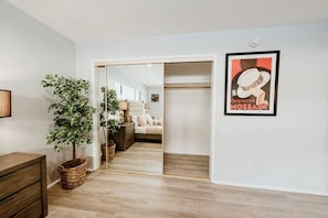 A bedroom with a bed, bedside tables, a plant, and a wardrobe.