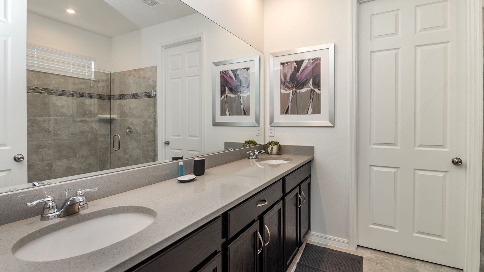 A modern bathroom with two sinks, a large mirror, and a shower.