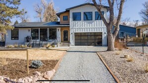 Ein zweistöckiges Haus mit Garage, überdachter Veranda und Auffahrt mit Kies.