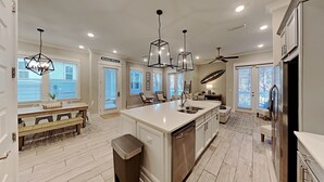 Uma cozinha ampla com uma ilha grande, iluminação pendente e ventilador de teto.