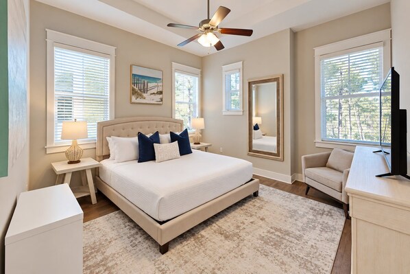 A bedroom with a large bed, a ceiling fan, and a view of the outdoors through the windows. - Hey Hey 30A - 3BR/2.5BA Prominence Home - Sleeps 8 - Golf Cart and 4 Bikes (Santa Rosa Beach)