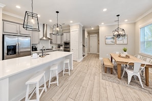 A modern kitchen with a large island, stainless steel appliances, and pendant lighting.