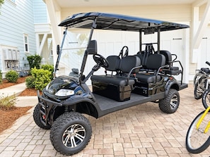 A golf cart parked in front of a house with a garage.