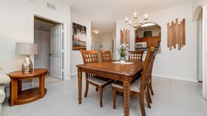 A dining area with a wooden table and chairs, a chandelier, and a painting on the wall. - 5 Star Condo on Windsor Hills Resort, Orlando Condo 4781 (Orlando)