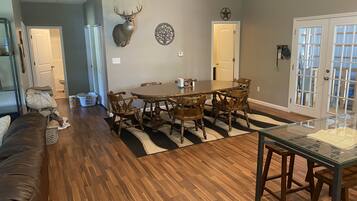 A dining area with a round wooden table and chairs, a chandelier, and a wall-mounted deer head.